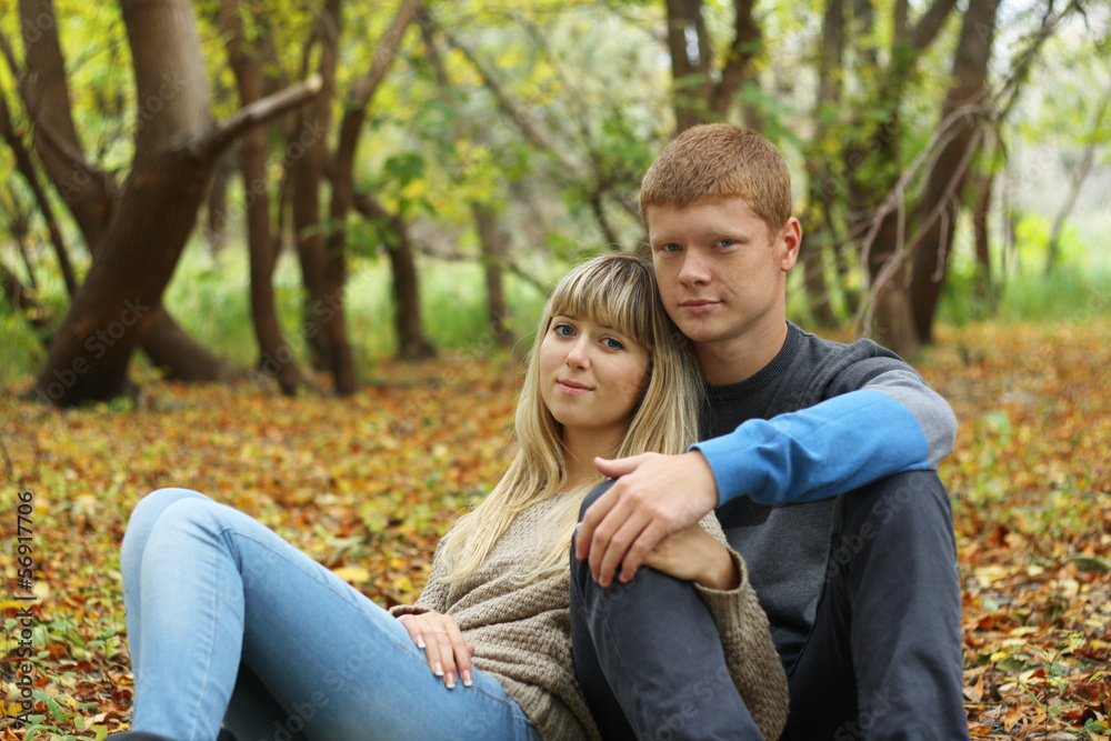 Young couple sitting on the foliage in autumn park Young couple sitting on the foliage in autumn park