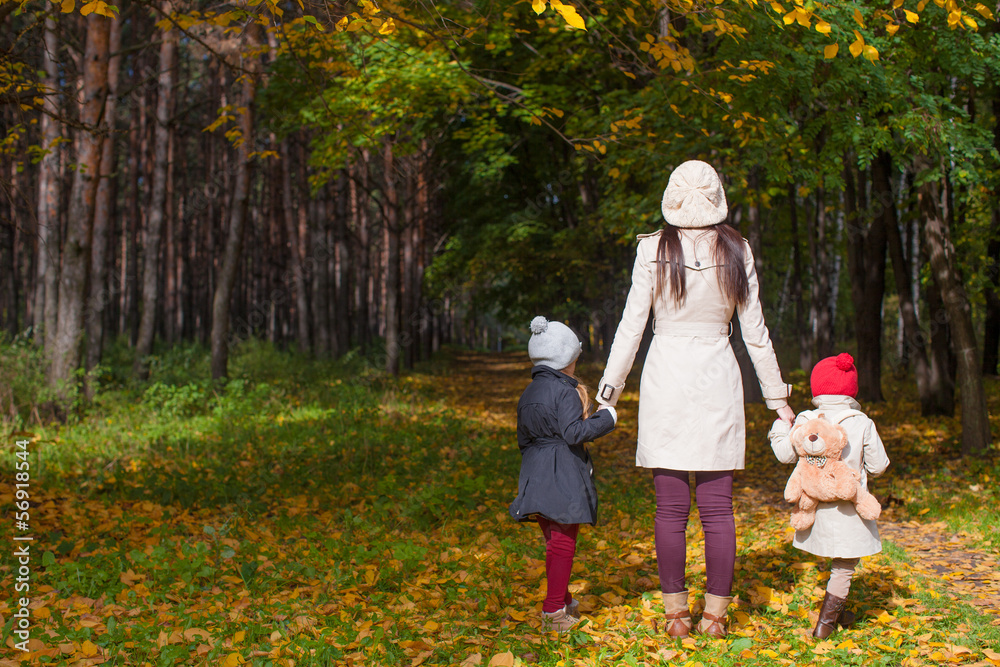 Back view of young mother and her cute little daughters walking Back view of young mother and her cute little daughters walking