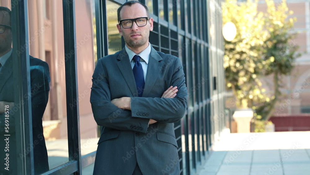 Portrait of serious young businessman stand by office building Portrait of serious young businessman stand by office building