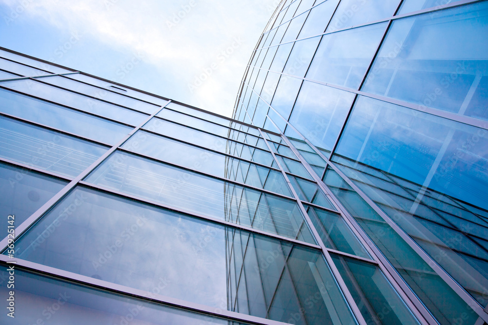 Obraz premium facade of modern glass blue office and clouds