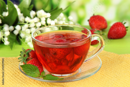 Delicious strawberry tea on table on bright background