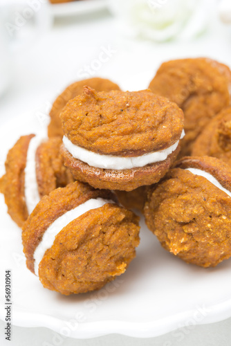 Pumpkin cookies with cream filling on the plate, close-up