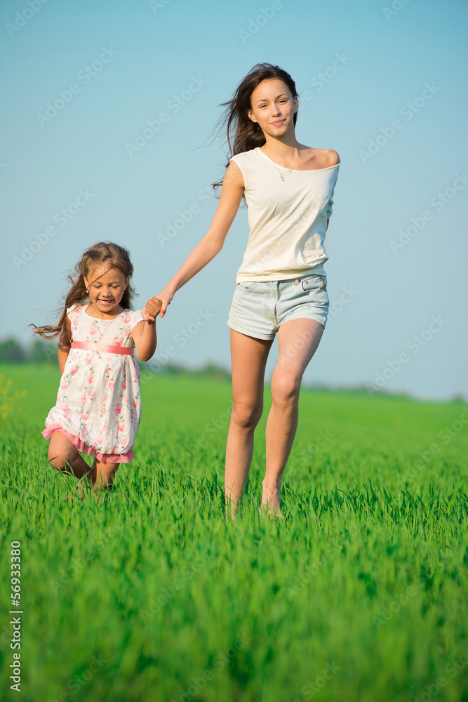 Young happy girls running at green wheat field
