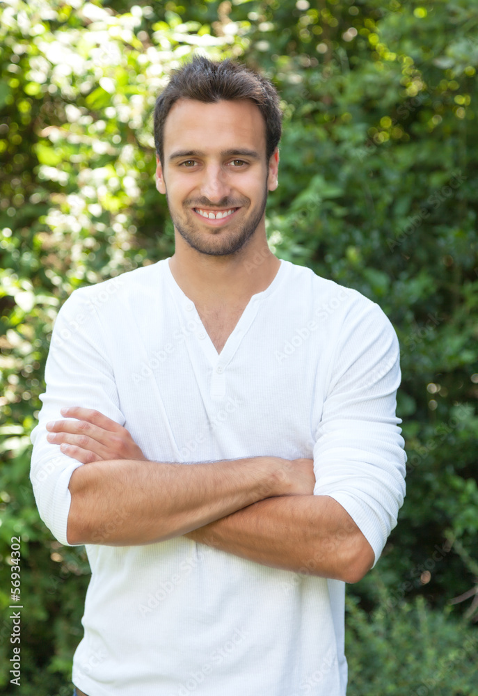 Laughing latinman with crossed arms in a park Laughing latinman with crossed arms in a park