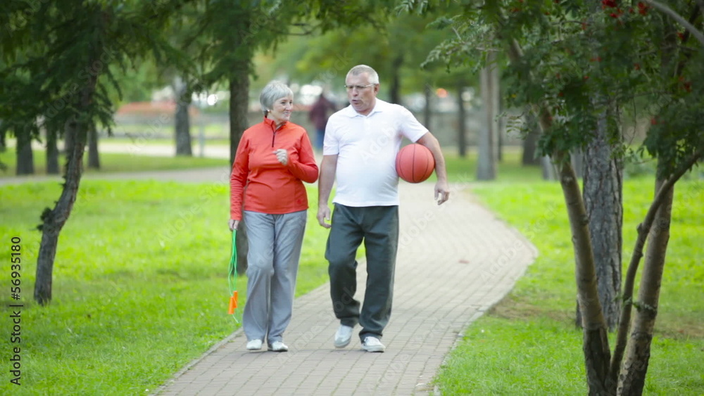 Active seniors walking along the park lane Active seniors walking along the park lane