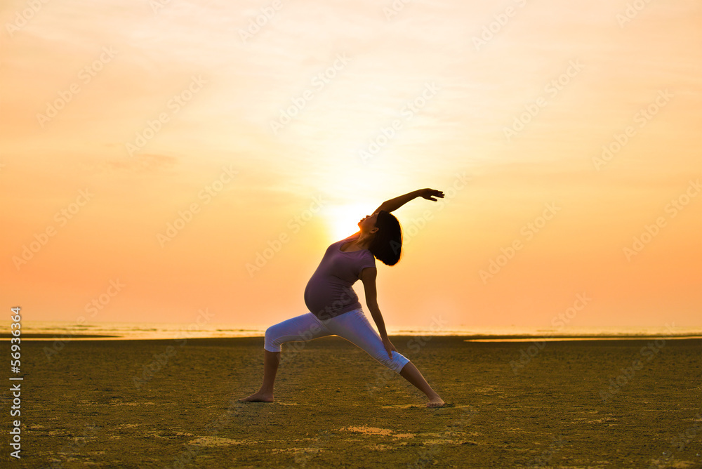 Fototapeta premium pregnant mother performing yoga on outdoor beach