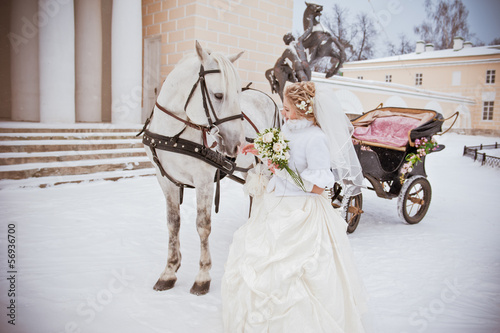 The beautiful bride with a horse in a winter park