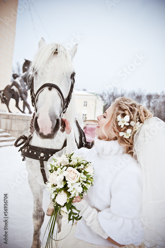 The beautiful bride with a horse in a winter park