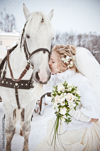 The beautiful bride with a horse in a winter park