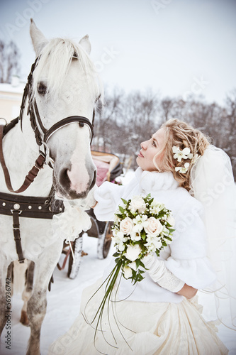 The beautiful bride with a horse in a winter park