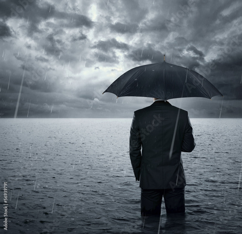 Businessman standing in the dramatic ocean before storm photo