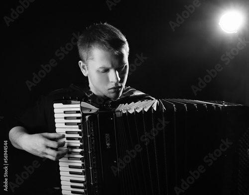 musician plays the accordion against a dark background