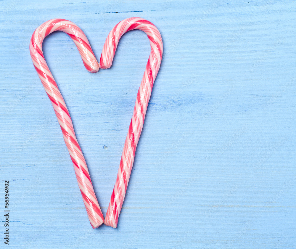 striped Christmas candies as a heart on wooden surface