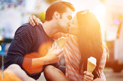 romantic couple kissing while holding ice cream photo