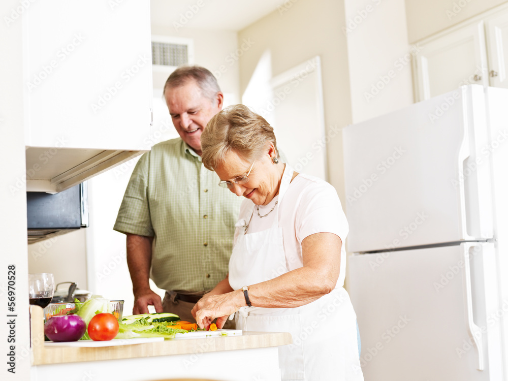 elderly married couple cooking dinner