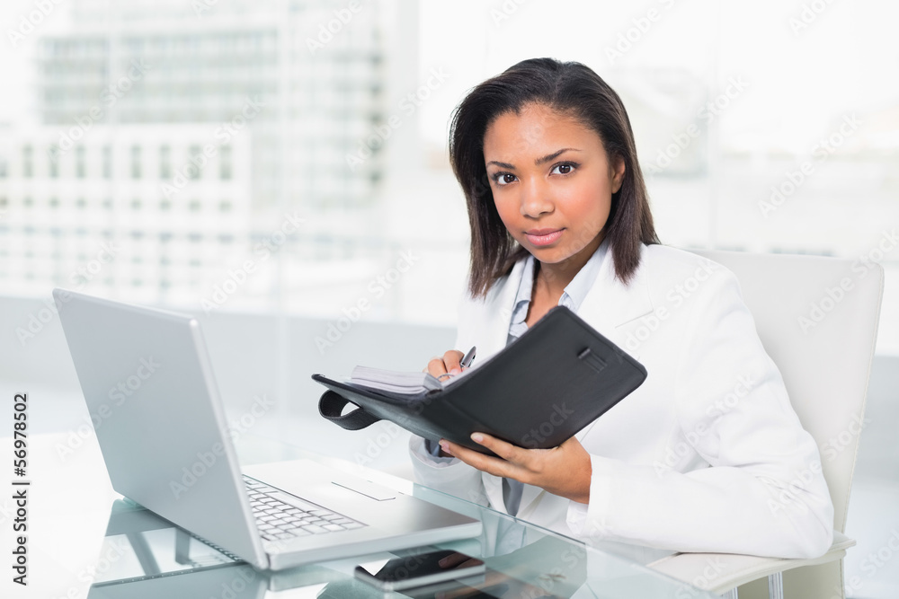 Serious young dark haired businesswoman filling her schedule Serious young dark haired businesswoman filling her schedule