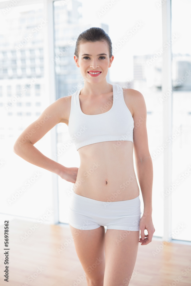 Happy fit brown haired model in sportswear posing with a hand on