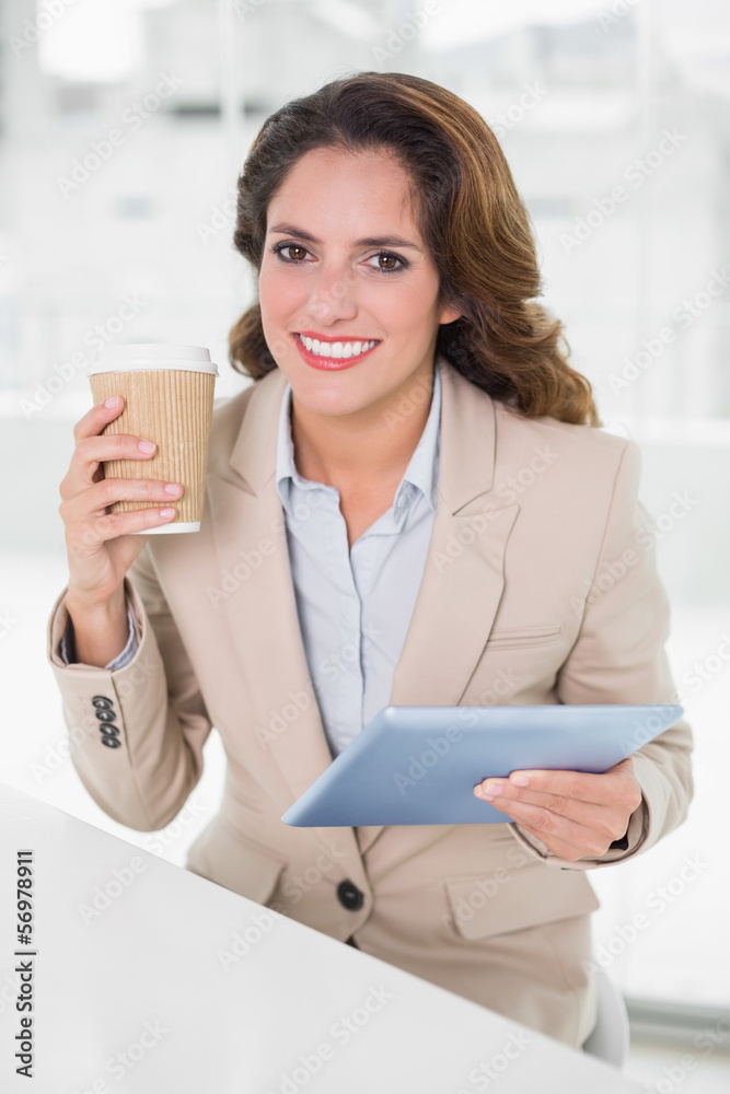 Cheerful businesswoman using digital tablet at her desk holding Cheerful businesswoman using digital tablet at her desk holding