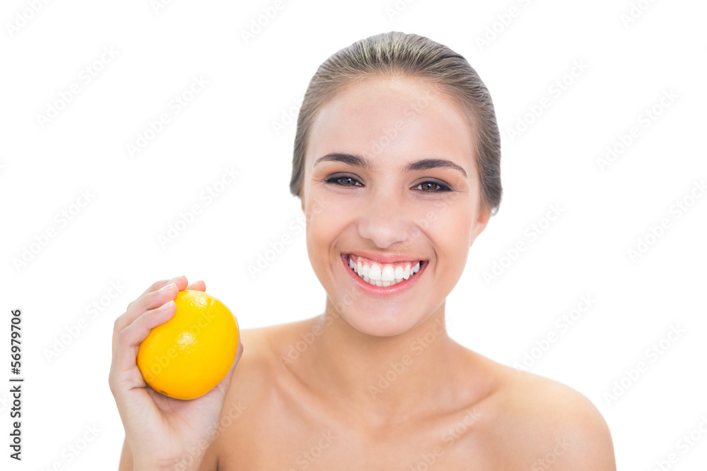 Happy young brunette woman holding an orange Happy young brunette woman holding an orange