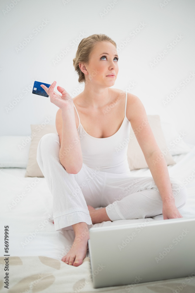 Natural thoughtful blonde holding credit card and sitting in fro Natural thoughtful blonde holding credit card and sitting in fro