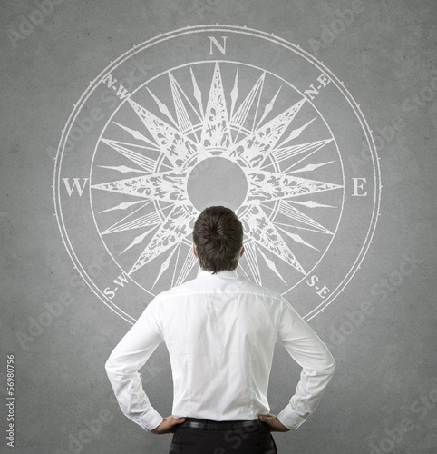 Canvas Print Confused, businessman looking at wind rose on the wall
