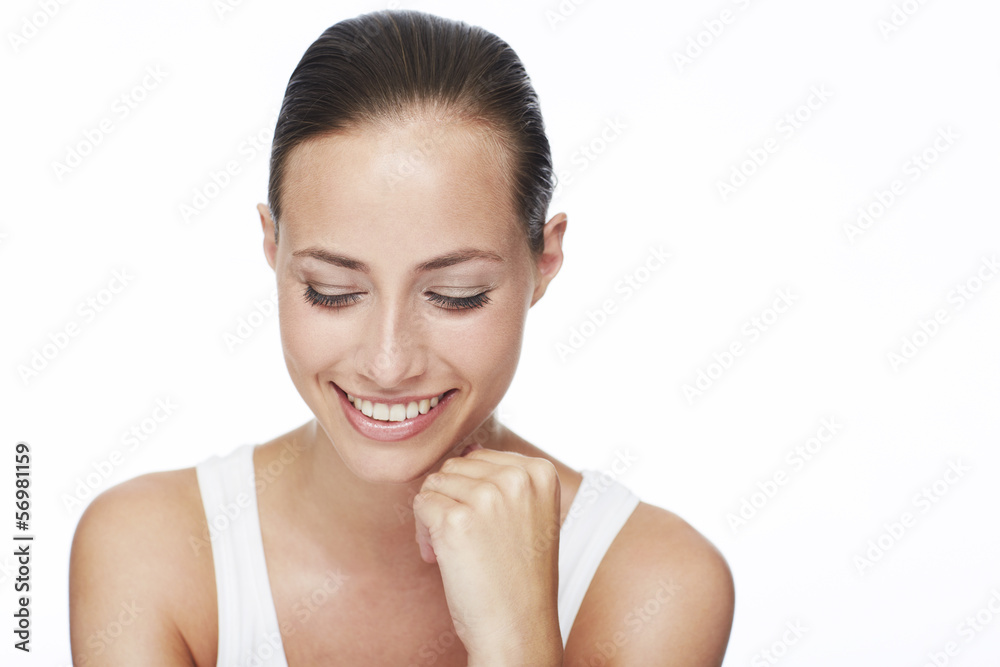Young woman looking down and smiling in studio Young woman looking down and smiling in studio