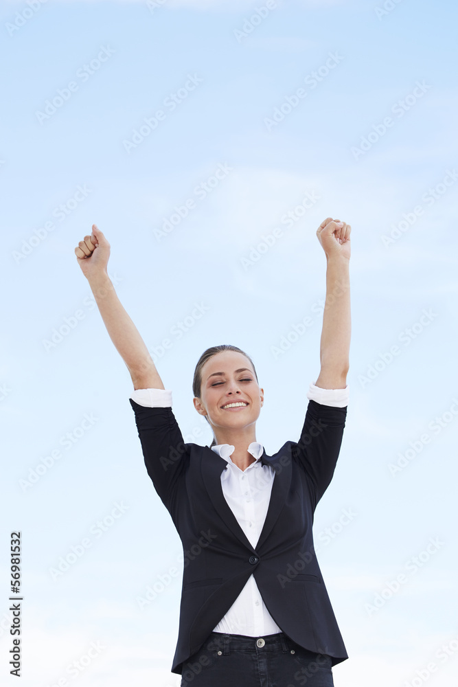 Young businesswoman with arms up against blue sky Young businesswoman with arms up against blue sky