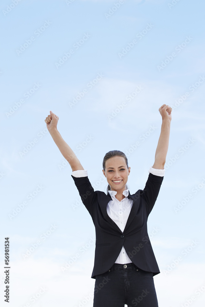 Young businesswoman with arms up against blue sky Young businesswoman with arms up against blue sky