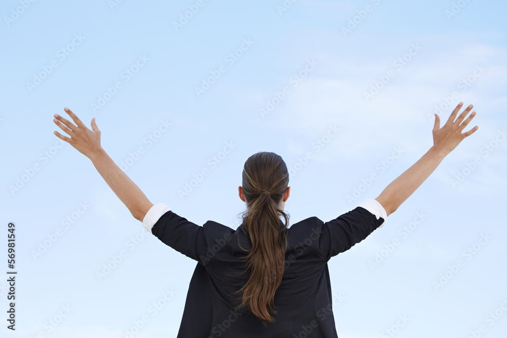 Businesswoman with arms out against blue sky, rear view Businesswoman with arms out against blue sky, rear view