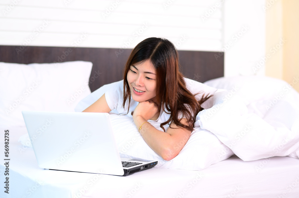 Asian teenage using laptop computer on bed Asian teenage using laptop computer on bed