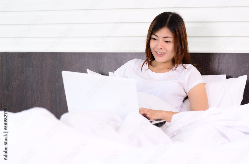 Asian teenage using laptop computer on bed Asian teenage using laptop computer on bed