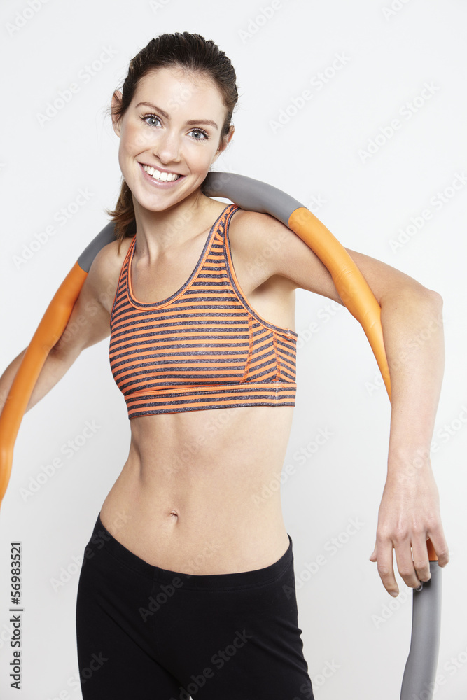 Young active woman standing with a hula hoop over her shoulders Young active woman standing with a hula hoop over her shoulders