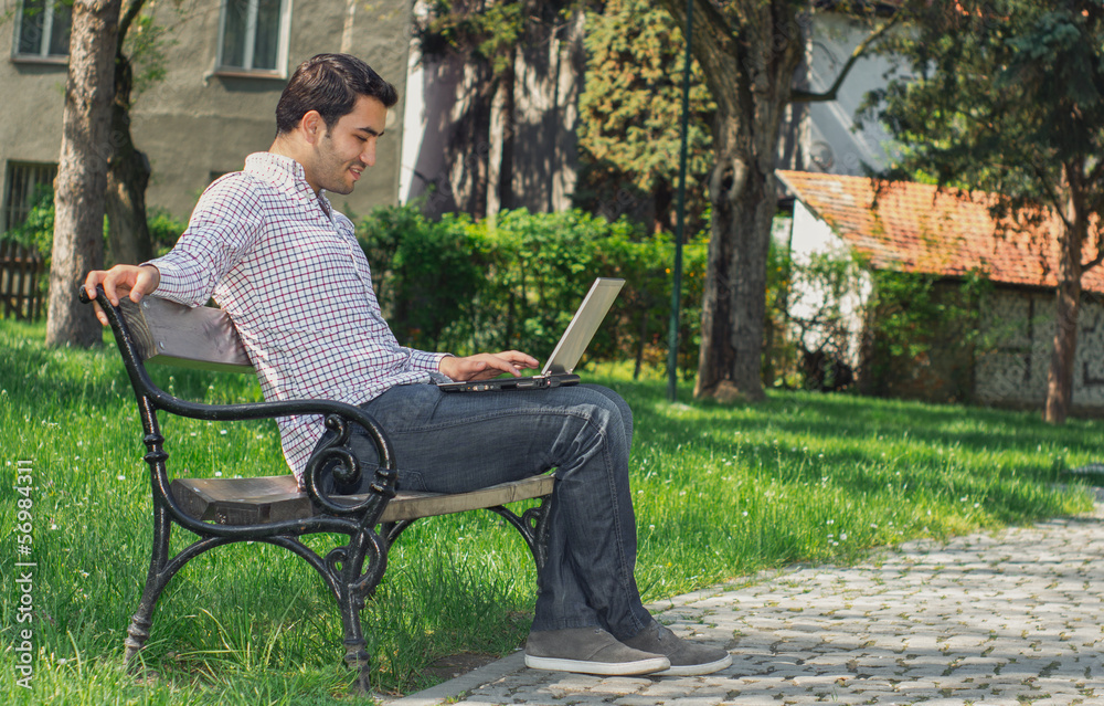 Happy man sitting on bench and using laptop Happy man sitting on bench and using laptop