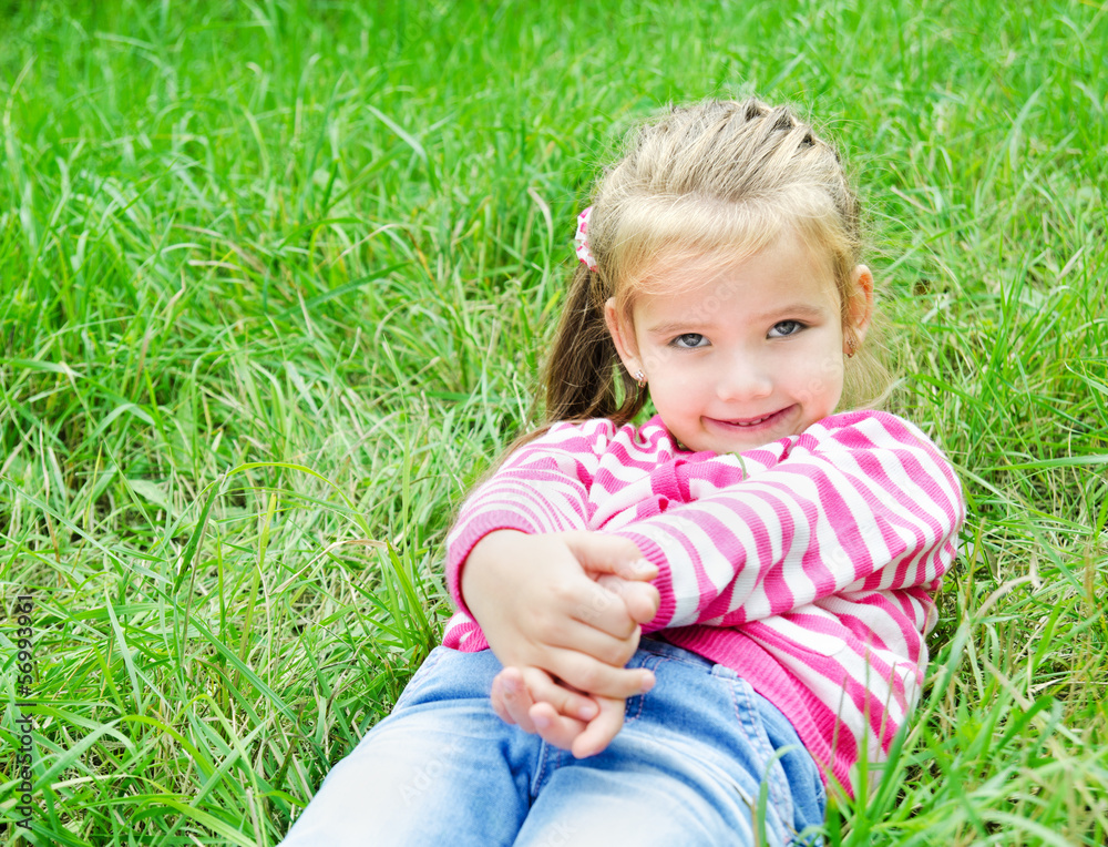 Cute smiling little girl lying in grass on the meadow Cute smiling little girl lying in grass on the meadow