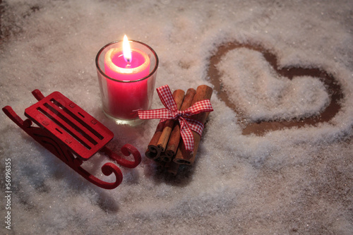 Schlitten und Kerze im Schnee