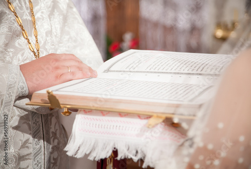 Priest giving Bible to bride during wedding ceremony photo