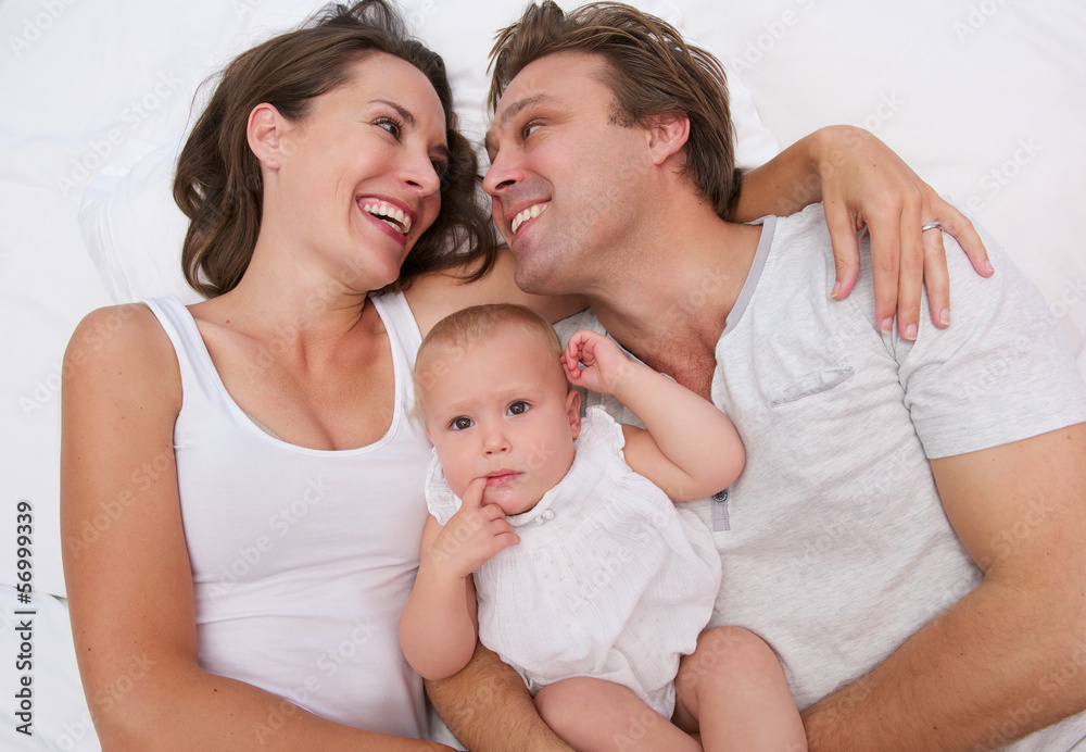 Portrait of a loving family holding cute baby in bed Portrait of a loving family holding cute baby in bed