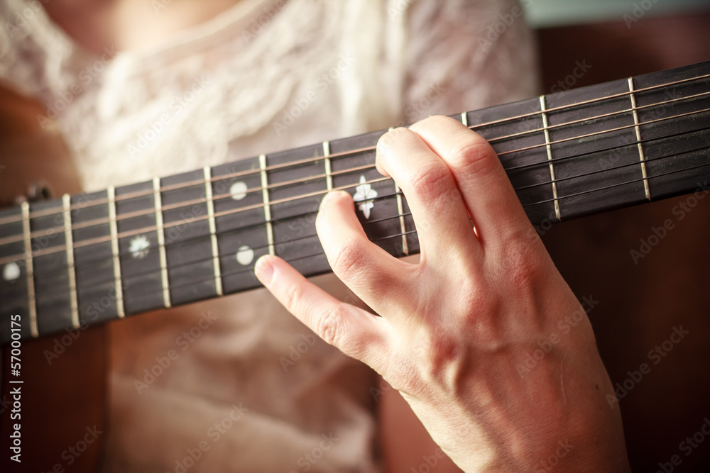 Clos eup on young woman's hand playing guitar