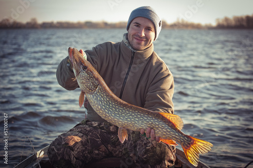 Happy angler with pike fishing trophy