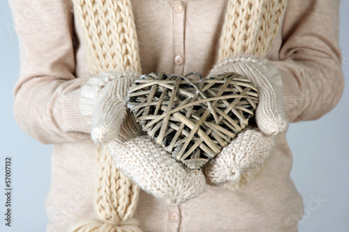 Female hands with wicker heart, close-up