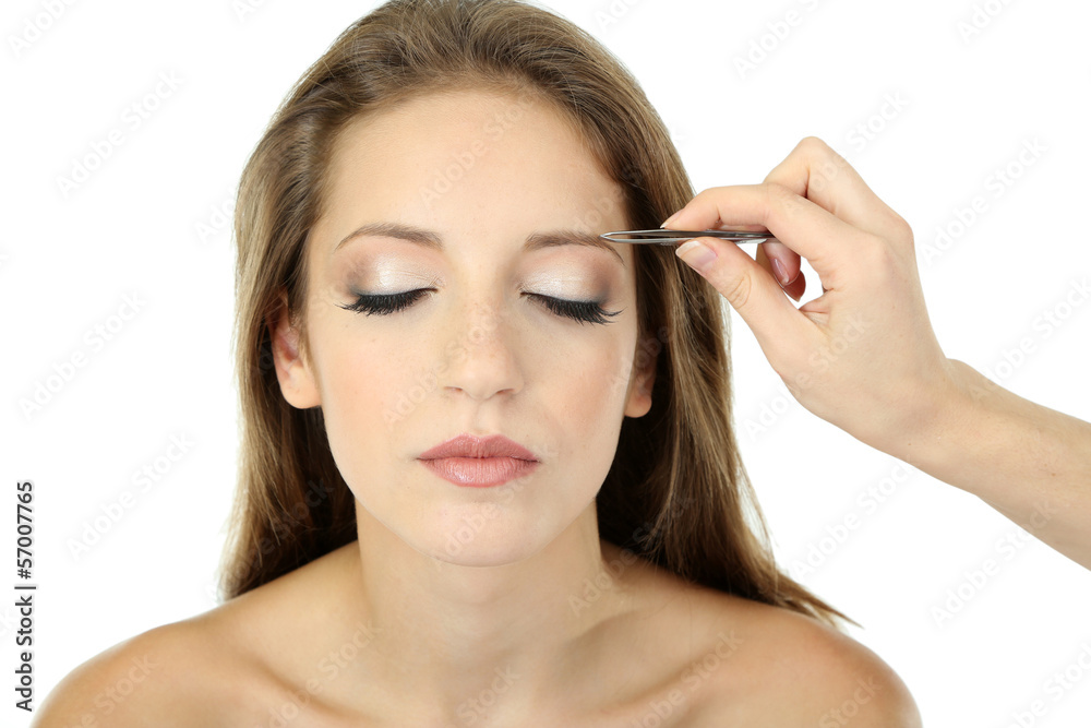 Young woman having eye-brows plucked isolated on white