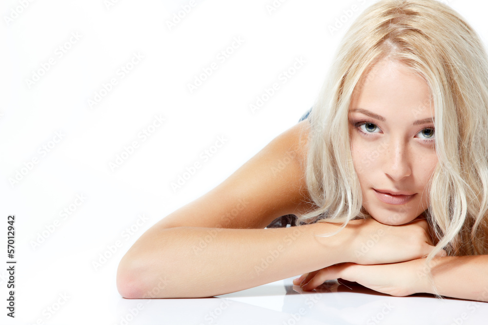 Fototapeta premium Beautiful blond teen girl lying and looking at camera. Isolated