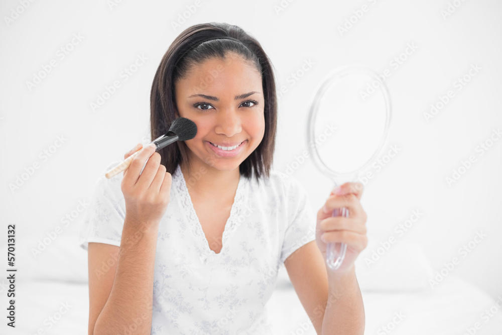 Content young dark haired model applying powder on her face Content young dark haired model applying powder on her face