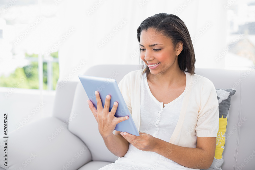 Content young dark haired woman in white clothes using a tablet Content young dark haired woman in white clothes using a tablet