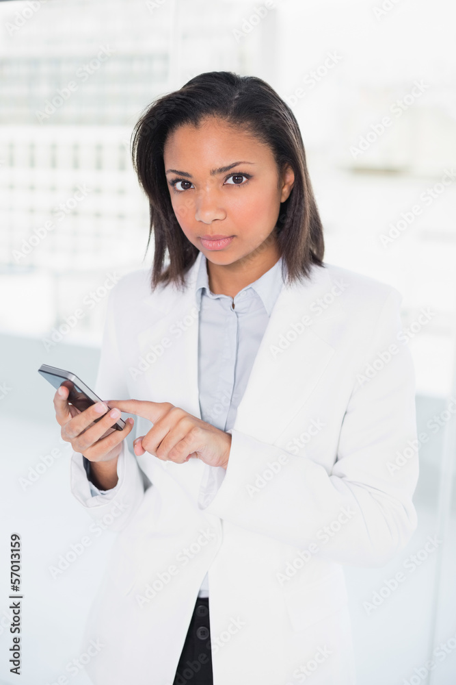 Stern young dark haired businesswoman using a mobile phone