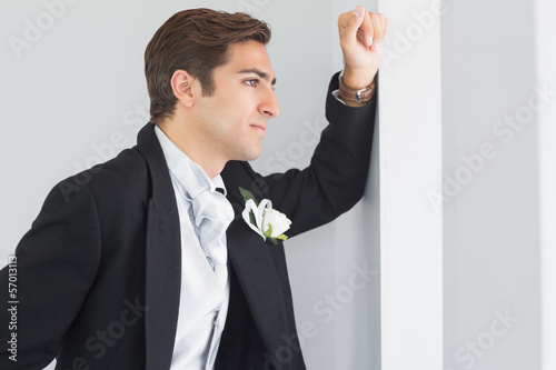 Serious bridegroom looking out of the window