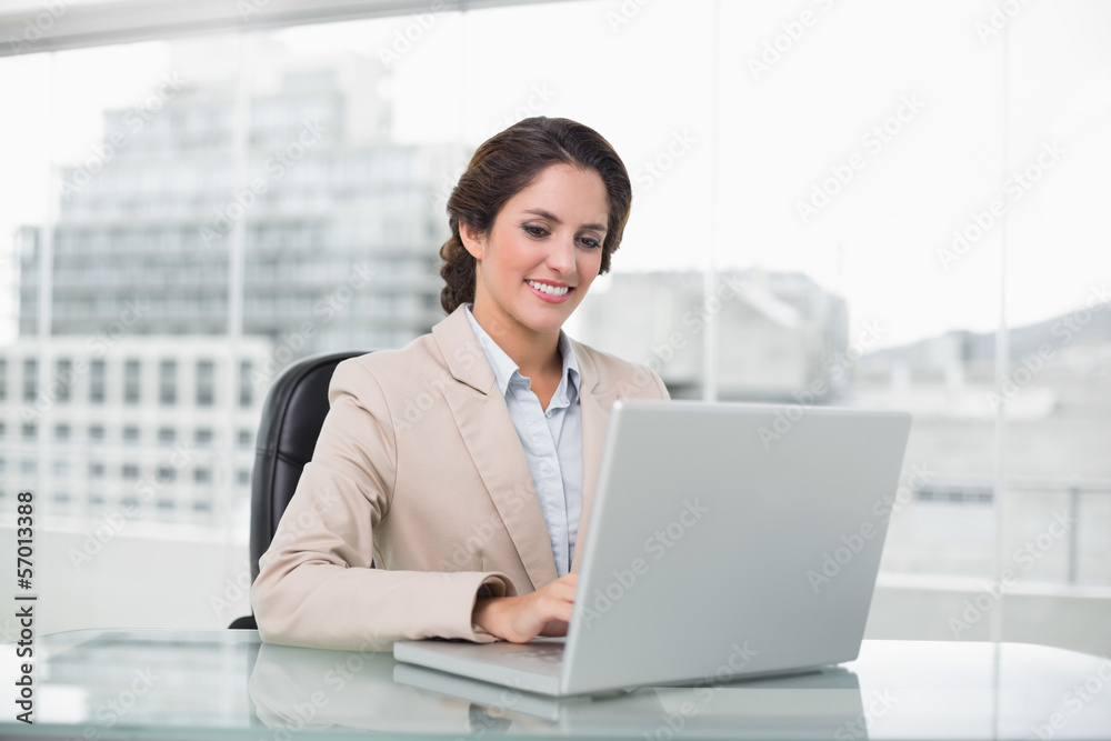 Happy businesswoman typing on laptop at her desk Happy businesswoman typing on laptop at her desk