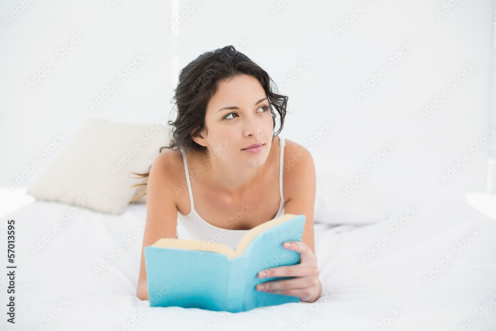 Thoughtful casual brunette in white pajamas relaxing on a bed re Thoughtful casual brunette in white pajamas relaxing on a bed re