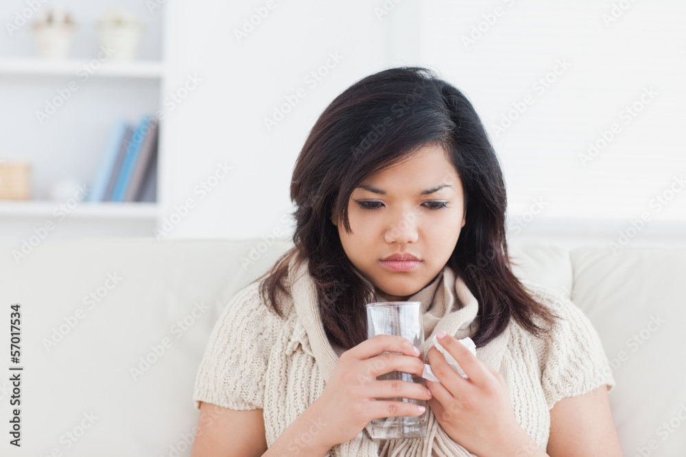 Woman holding a glass of water while being cold