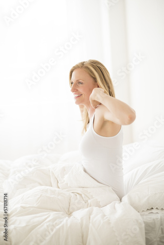 Young Woman Stretching While Sitting In Bed
